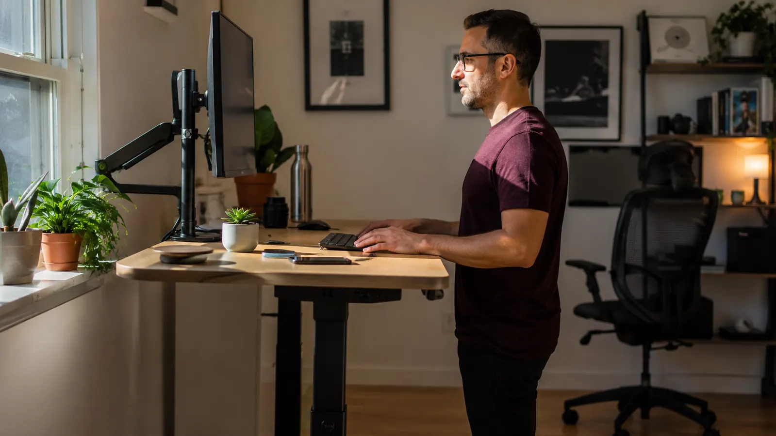 Person walking at a slight incline on an under-desk walking pad treadmill in a bright home office, viewed from the side