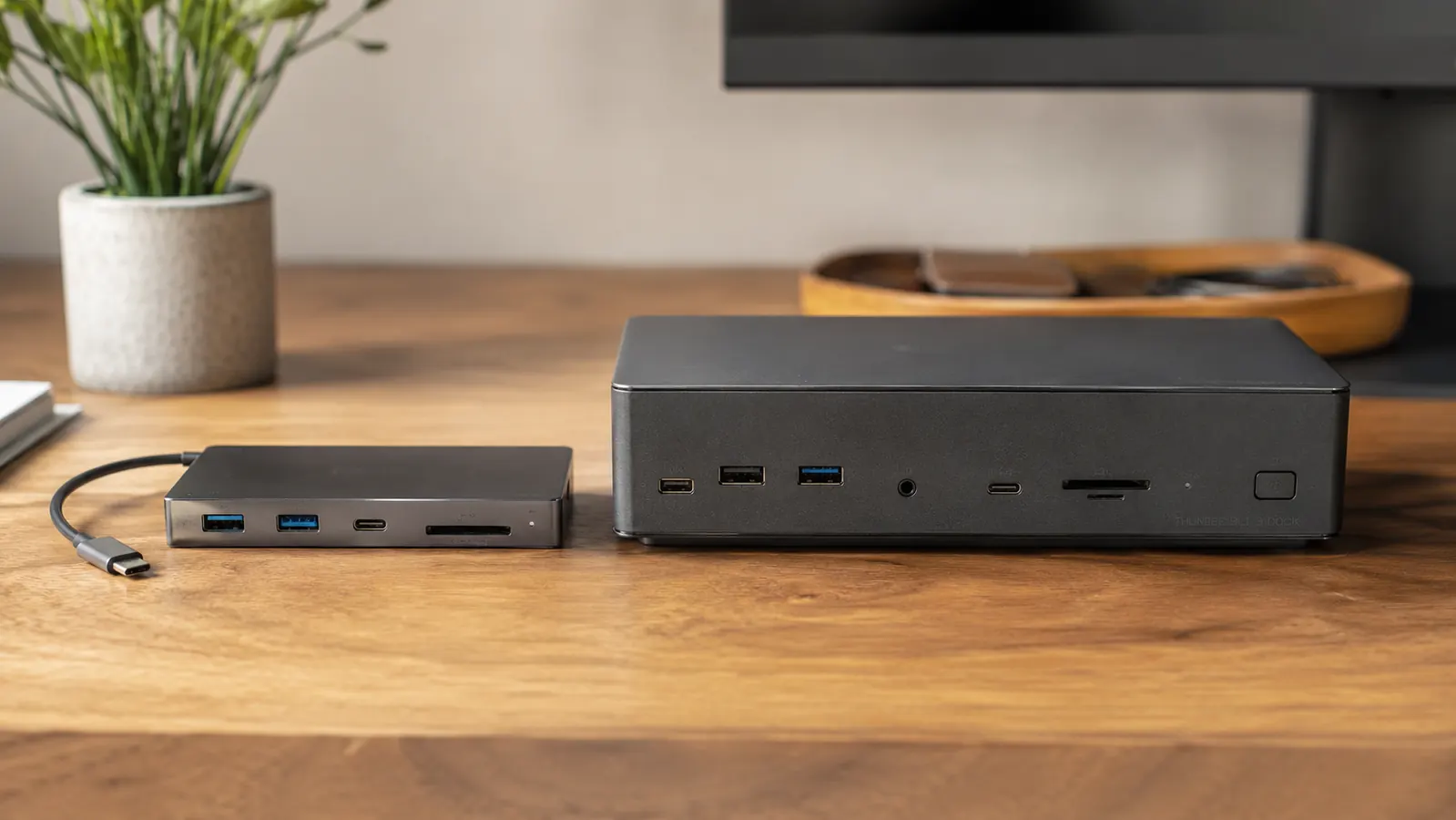 Clean home office desk with a laptop connected to a small USB-C hub, monitor, keyboard, and mouse on a wooden surface